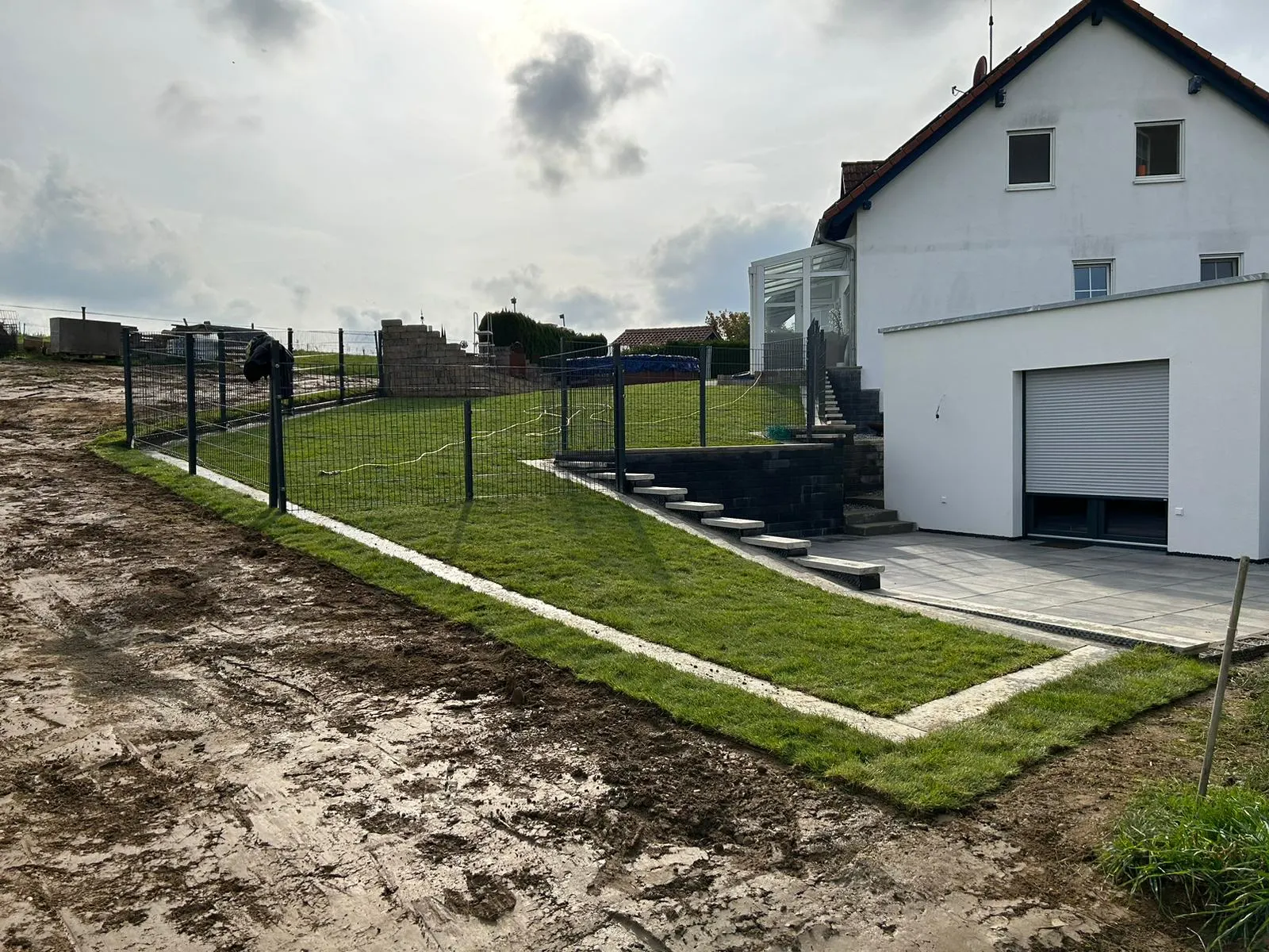 Neu angelegte Rasenfläche mit Stabmattenzaun an einem Hang